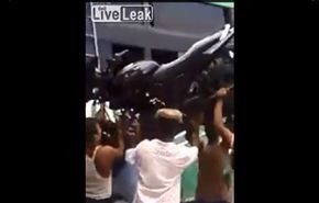 بالفيديو/ يحمل دراجته النارية على رأسه ويعتلي بها الحافلة