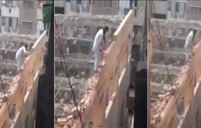 بالفيديو.. عامل يهدم جدار مبنى شاهق وهو واقف فوقه!