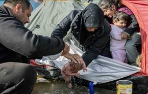 صور صادمة لعائلة سورية لاجئة تغسل رضيعا في العراء