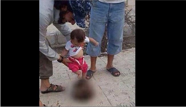 صورة/داعشي يشجع طفله الرضيع على ركل رأس مقطوعة بالرقة