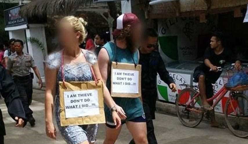 سائحان في إندونيسيا يحملان لافتة 