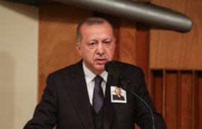 أردوغان يعلق على صدره صورة مسؤولة في الرئاسة التركية