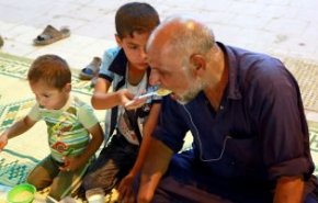 شاهد.. طفل عراقى يطعم والده المبتورة يداه فى إفطار رمضان
