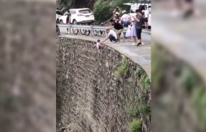 بالفيديو.. أب يعلق ابنه من فوق الجبل لإلتقاط صورة!