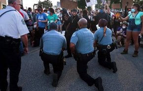 شماری از افسران پلیس آمریكا در اعتراض به خشونت همکارانشان، مقابل تظاهرکنندگان زانو زدند