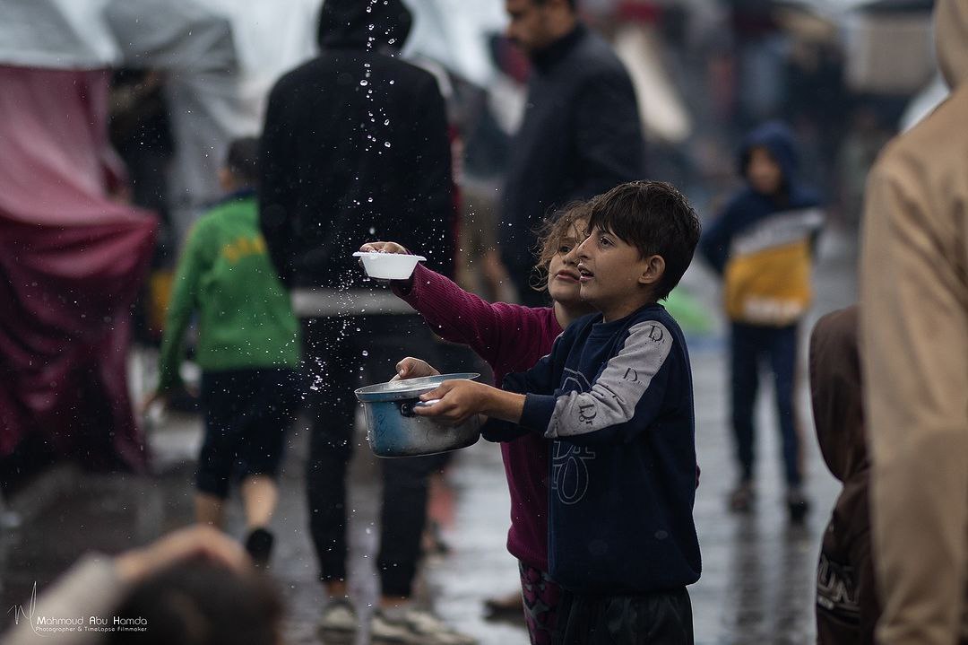 أطفال يحاولون جمع مياه الأمطار في ظل شحّ الماء والطعام في قطاع غزة